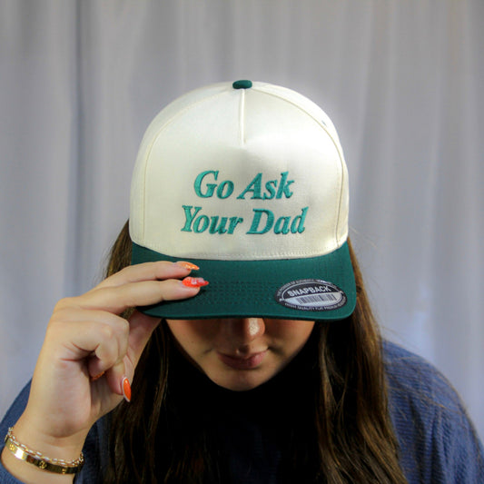 Person wearing a cap with 'Go Ask Your Dad' text against a plain background